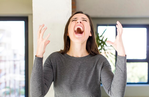 Foto urlando furiosamente sentendosi stressato e infastidito con le mani in alto dicendo perché me