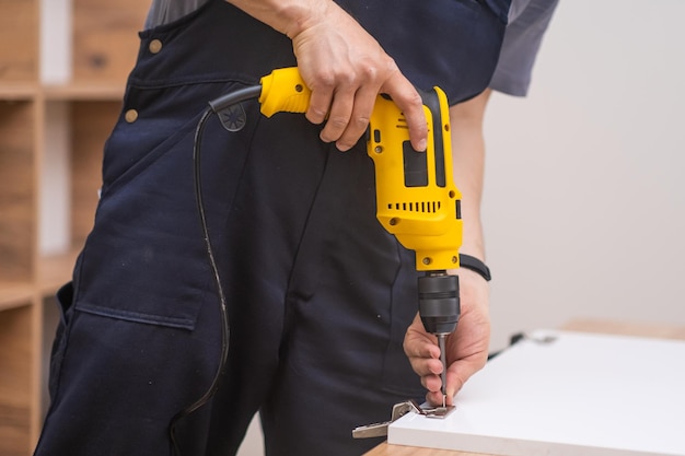 Furniture delivery and assembly handyman attaching white door to wooden cabinet