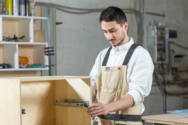 Furniture factory, Small-Sized Companies and people concept - Young worker works in a factory