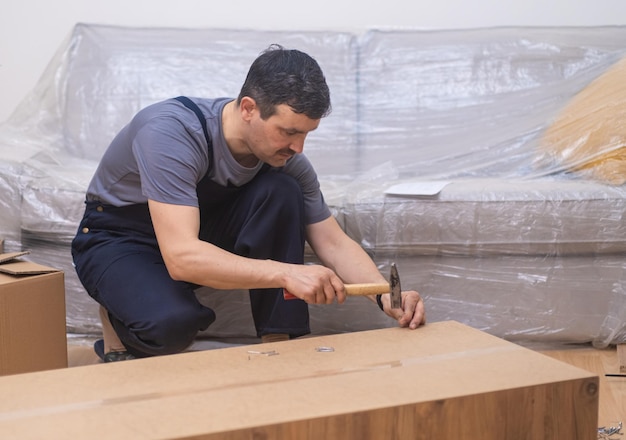 Furniture fixing process firm worker in overalls hammering tiny nails