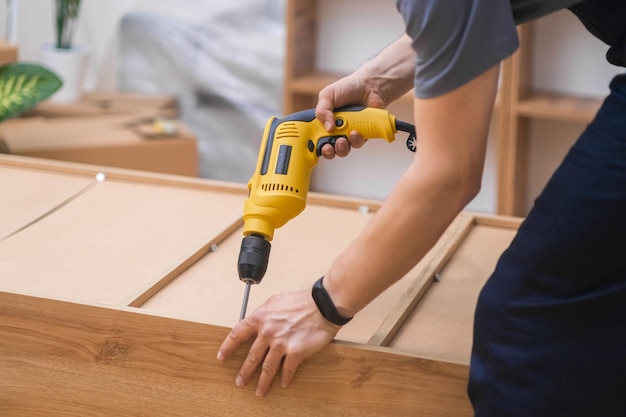 Мебель из качественных древесных материалов, процесс сборки, плотник использует электрическую отвертку