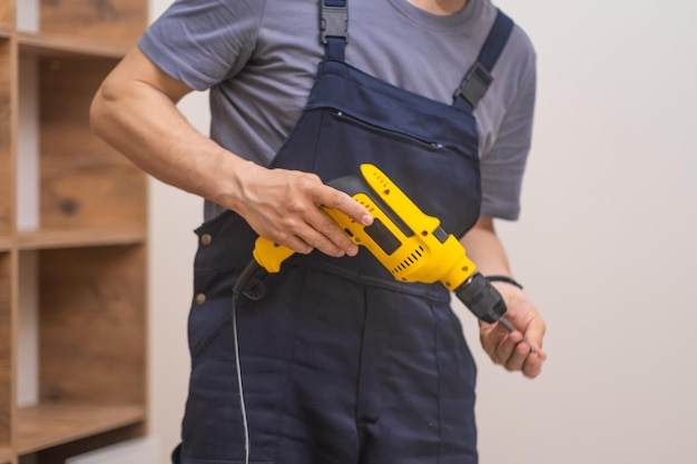 Furniture manufacturing and delivery handyman in uniform using electric screwdriver