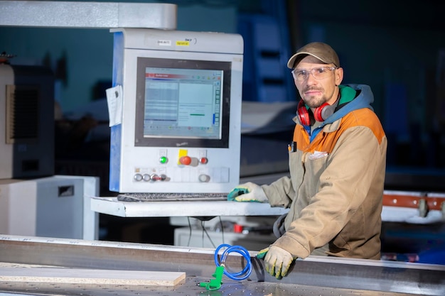 A furniture production worker behind a programmed machine makes\
furniture parts. furniture manufacturing.