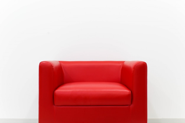Furniture red sofa is located next to the white cement wall.