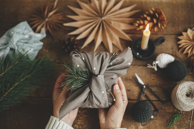 Furoshiki kerstcadeau Handen met stijlvol cadeau verpakt in bruine stof op rustiek Geen afval