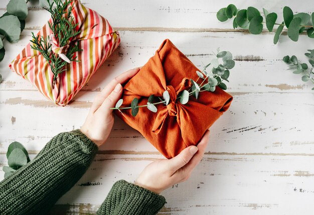 Furoshiki tissue wrapping of presents Female hand holding a gift in eco friendly reusable fabric