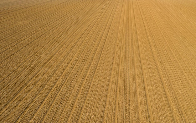 Furrows row pattern in a plowed field prepared for planting crops in spring time, drone point of view shot