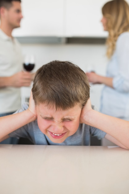 Orecchie coprenti del ragazzo di furstrated mentre discussione dei genitori