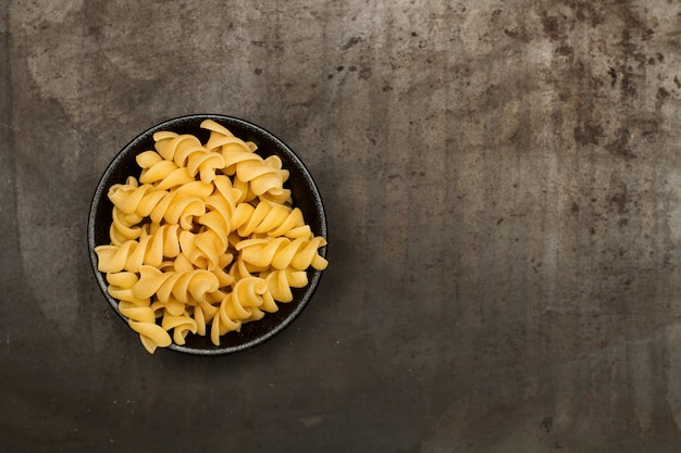 Fusilli in a black bowl on a metal table in a top vi