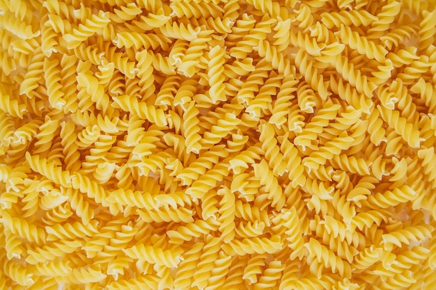 Fusilli pasta als achtergrondafbeelding. Afbeelding textuur spiraal macaroni. Bovenaanzicht. Kopiëren, lege ruimte voor tekst.
