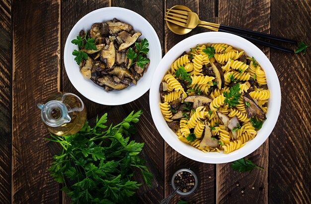 Fusilli pasta gluten free with forest mushrooms on a white plate. Vegetarian / vegan  food. Italian cuisine. Top view, flat lay, copy space