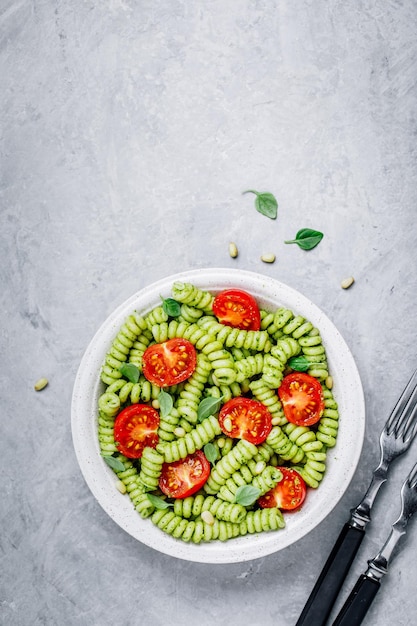 Fusilli-pasta met basilicum-pestosaus, tomaten en pijnboompitten Bovenaanzicht kopieerruimte