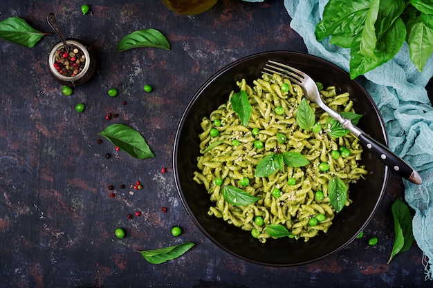 Fusilli-pasta met pestosaus, groene erwten en basilicum. Italiaans eten. Bovenaanzicht. Plat leggen.