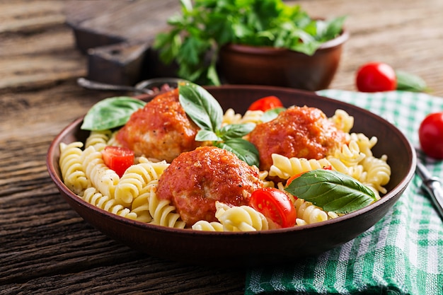 Fusilli pasta with meatballs in tomato sauce and basil in bowl