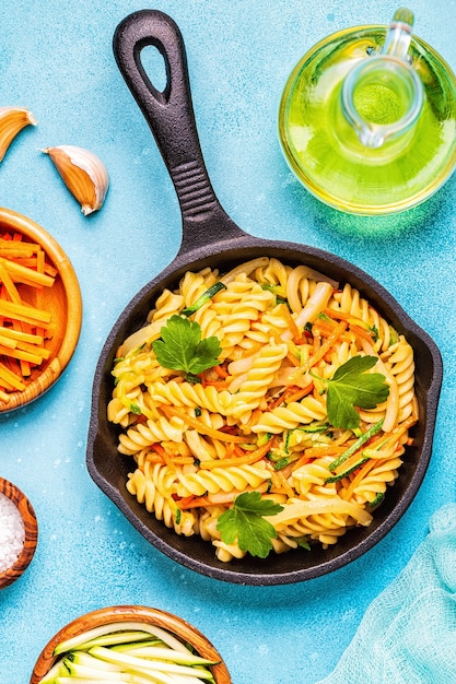 Fusilli pasta with squid, zucchini and carrots, top view.