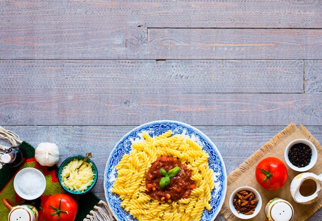 Fusilli pasta with tomato sauce and vegetables on a wooden table