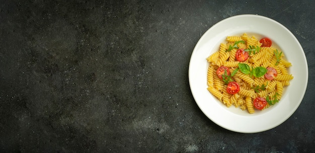 fusilli pasta with tomatoes, herbs and basil on a white plate