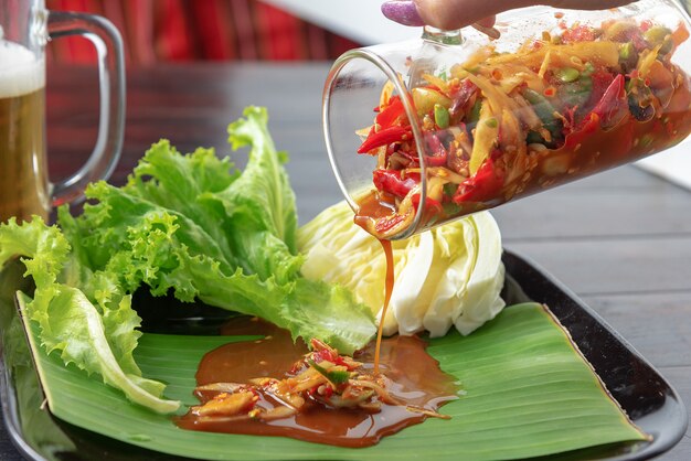 Fusion food for somtum in glass pouring on banana leaf