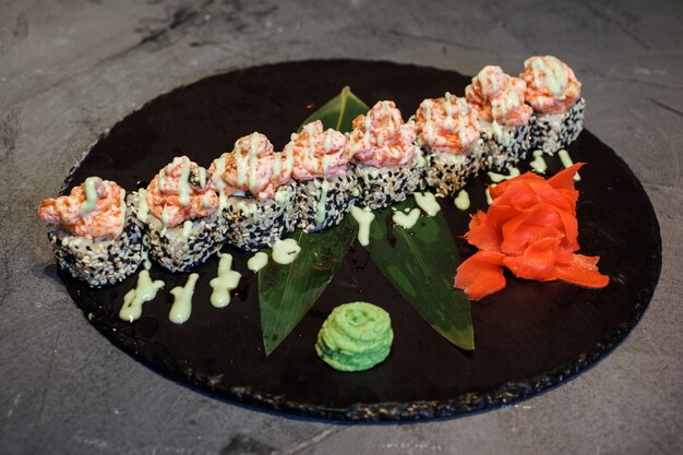 Foto fusion rijstrolletjes, sushi maki op het zwarte bord met wasabi en gember.