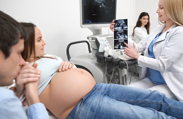 Future father kissing hand of pregnant wife in clinic