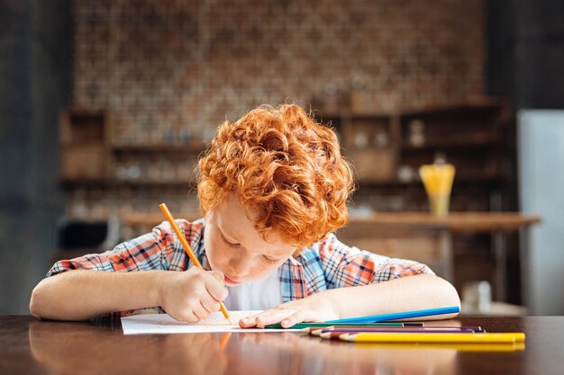 Future great artist. Adorable little boy sitting at a table and concentrating on a piece of paper while working on his next masterpiece at home.