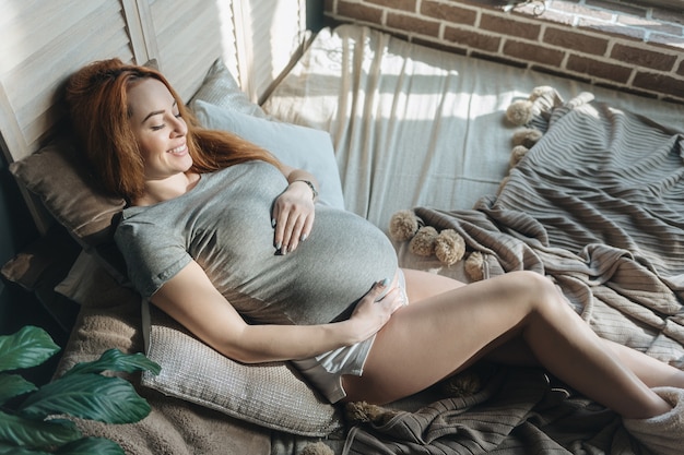 Futura mamma posa sul letto di riposo mentre si tocca la pancia