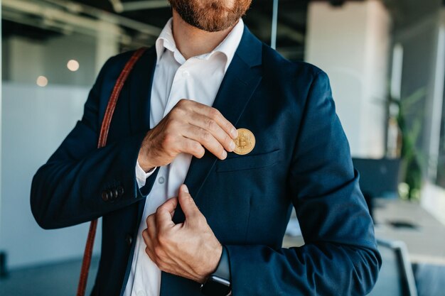 将来のお金とビットコインのコンセプトでの生活オフィスのインテリアを歩くポケットに合わせてビットコインを置く投資家の男性
