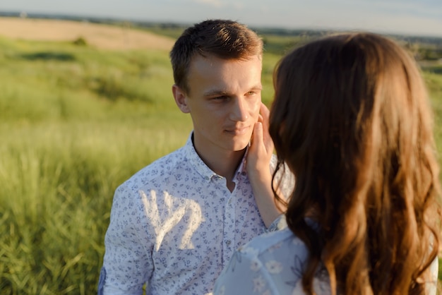 Future mum and dad kissing in the park at sunset