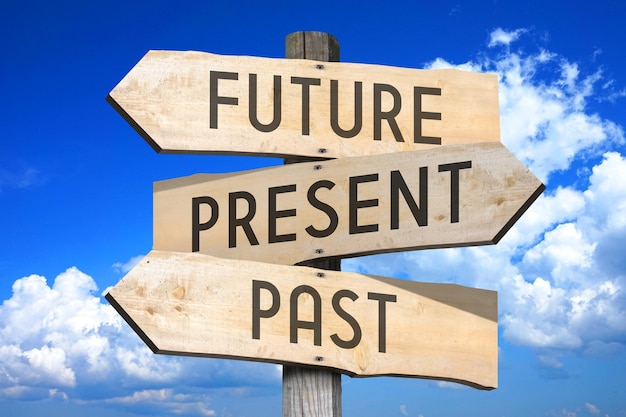 Future present past wooden signpost with three arrows sky with clouds in background