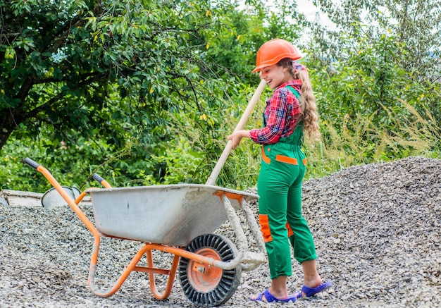 Future profession future engineer happy kid use construction\
wheelbarrow building construction site child architect worker labor\
day concept childhood development teenager girl assistant