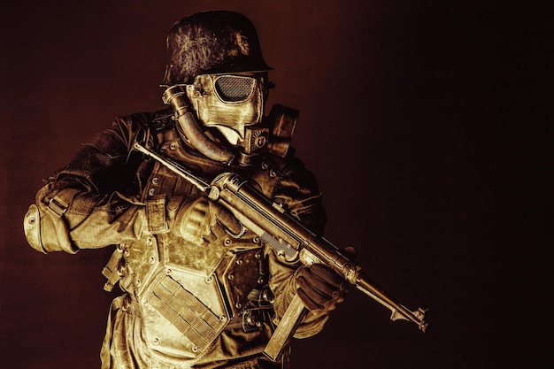 Futuristic nazi soldier gas mask and steel helmet with schmeisser handgun black background studio shot