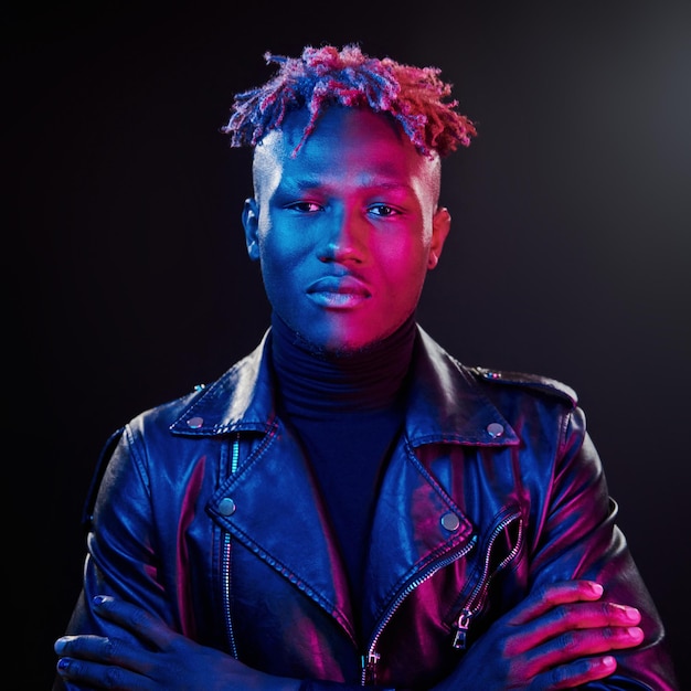 Futuristic neon lighting Young african american man standing in studio with arms crossed