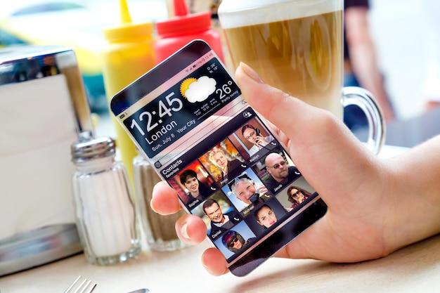 人間の手に透明なディスプレイを備えた未来的なスマートフォン。実際の将来の革新的なアイデアと最高の技術の人類を概念化します。