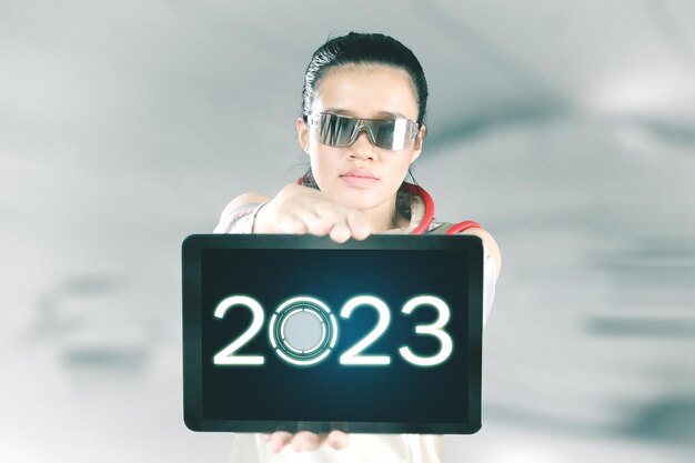 タブレットで 2023 年の数字を示す未来的な女性