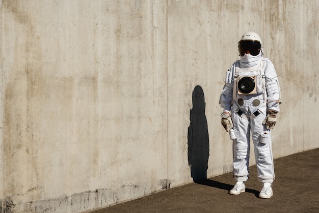 Futuristische astronaut in een helm tegen grijze muren. fantastisch kosmisch kostuum.