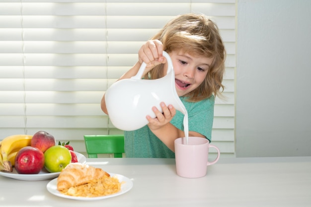 Fuuny little boy pouring whole cows milk for breakfast child boy eating organic healthy food healthy