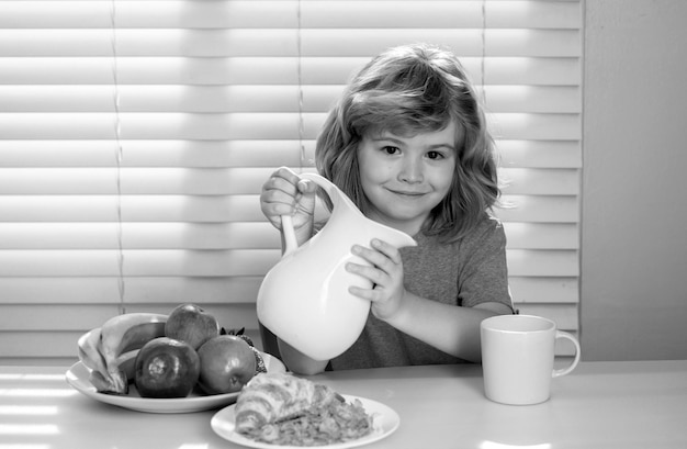 Photo fuuny little boy pouring whole cows milk for breakfast funny blonde little boy having breakfast milk