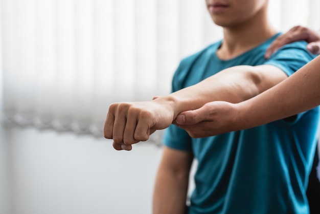 Fysiotherapeut die een man behandelt met elleboogpijn in een kliniek.