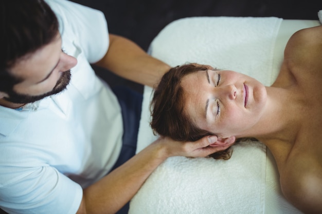 Fysiotherapeut die hoofdmassage geeft aan een vrouw