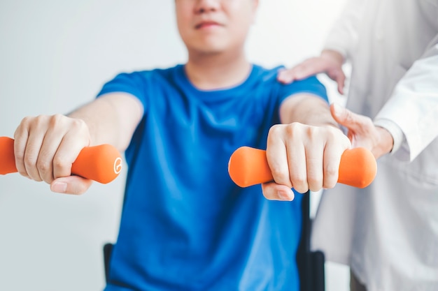 Fysiotherapeut man geeft oefening met halter behandeling over Arm en schouder van atleet mannelijke patiënt Fysiotherapie concept