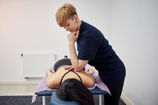 Fysiotherapeut masseert een vrouwelijke patiënt sportvrouw met beschadigde spieren in kinesio kliniek Behandeling van sportblessures