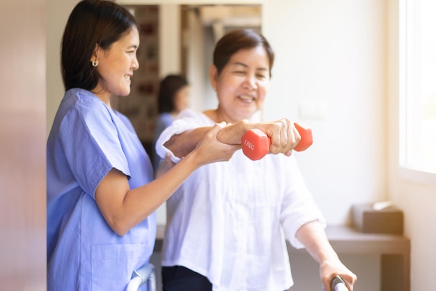 Fysiotherapeut vrouw training met senior patiënt met dumbbells in kliniek, fysiotherapie concept