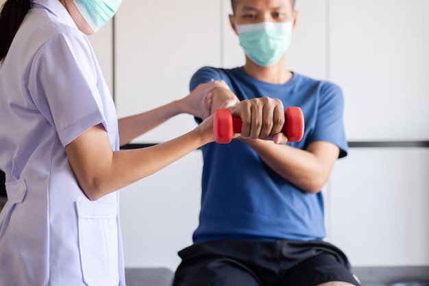 Fysiotherapeut vrouwen trainen met mannen patiënt met behulp van halters in kliniek, fysiotherapie concept