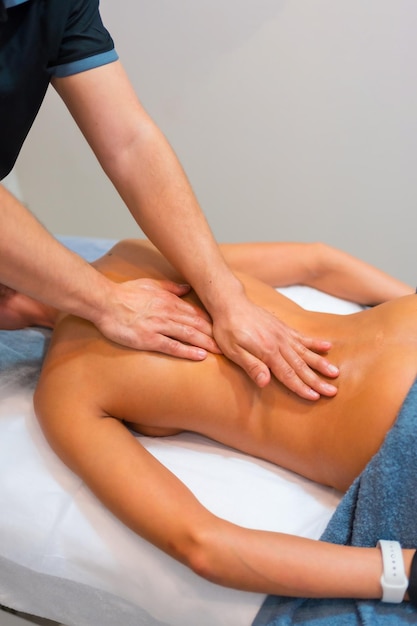 Fysiotherapeutische massage aan een onherkenbare vrouw die op een brancard op haar rug ligt
