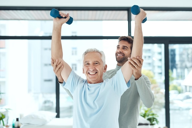 Fysiotherapie werkt Shot van een vriendelijke fysiotherapeut die zijn oudere patiënt helpt bij het trainen met gewichten