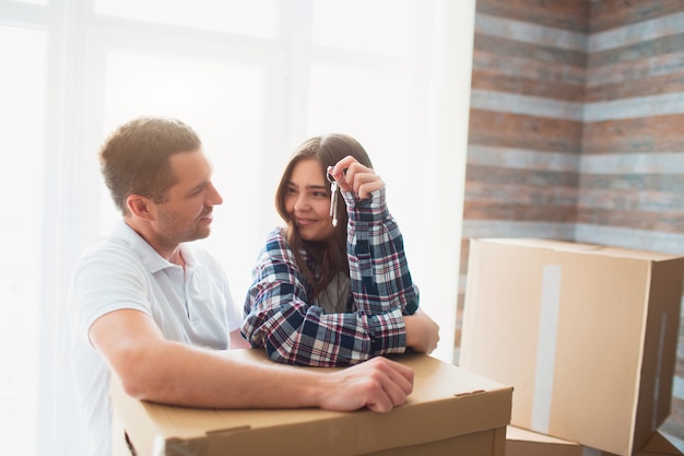 Ga naast kartonnen dozen staan en kijk naar elkaar. In de handen van zijn vrouw de sleutels van een nieuwe woning, appartement, huis