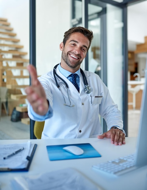Ga zitten en laten we uw gezondheid bespreken Portret van een jonge dokter die een handdruk uitsteekt in zijn kantoor