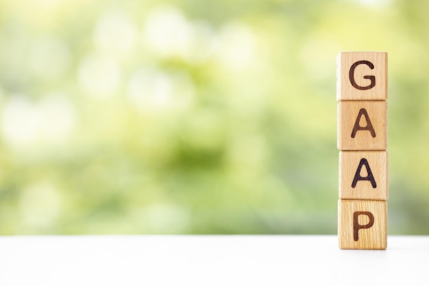 GAAP word is written on wooden cubes on a green summer background Closeup of wooden elements