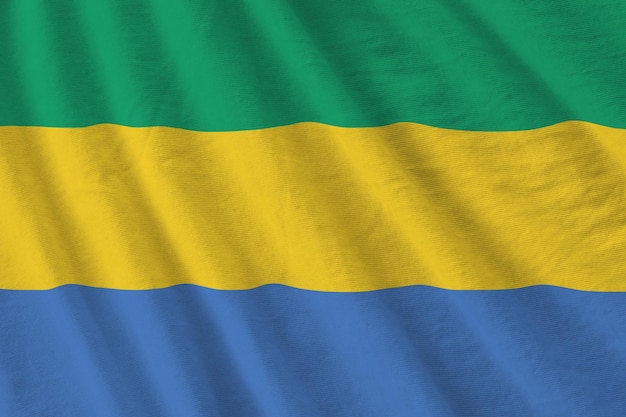 Gabon flag with big folds waving close up under the studio light indoors The official symbols and colors in banner