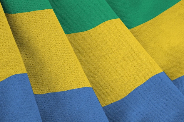 Photo gabon flag with big folds waving close up under the studio light indoors the official symbols and colors in banner